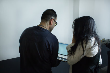 portrait from behind of a man and executive woman working with a laptop in a workshopの写真素材