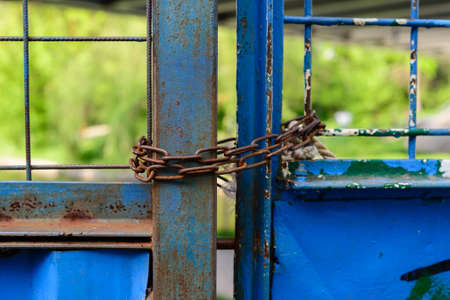 Close-up of blue rusty gates locked with chains の写真素材