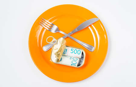 Rolls of banknotes in tin can served in an orange plate on white backgroundの写真素材