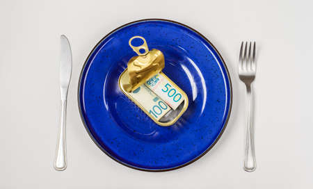 Rolls of banknotes in tin can served in a blue plate on white backgroundの写真素材