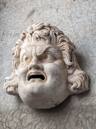 Ancient roman head statue showing anger on a wall in the Vatican cityの写真素材