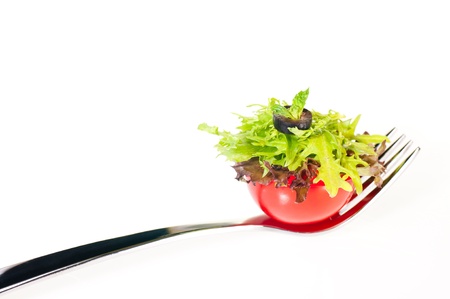 Fresh salad piled on half cherry  tomato on a forkの写真素材