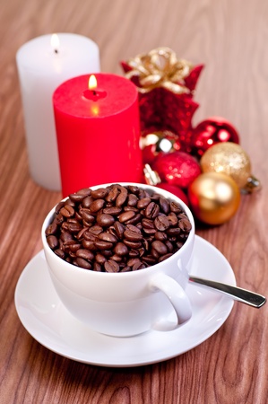 Christmas cup of coffee beans with candles and ornaments over wood backgroundの写真素材