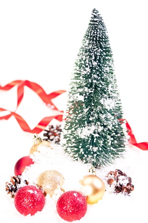 Mini Christmas tree with pinecone, red and gold baubles on snowの写真素材