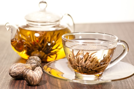 Blooming green tea in glass teacup close up with teapot  various dry blooming tea on the tableの写真素材