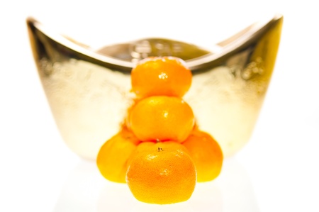 A stack of tangerine with large ingot as backgroundの写真素材