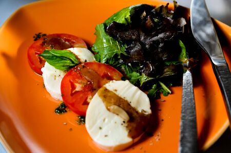 Tomato mozzarella salad close up on a orange plateの写真素材