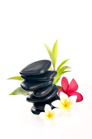 Eight balanced zen stones with red and white plumeria flower and bamboo plant over whiteの写真素材