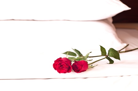 Romantic setting on a bed with red roses の写真素材