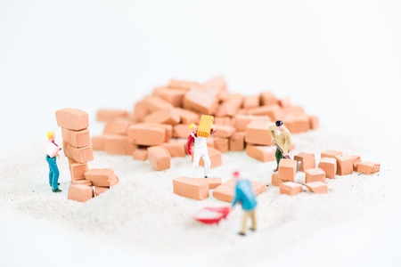 Miniature workmen working together in laying bricks の写真素材
