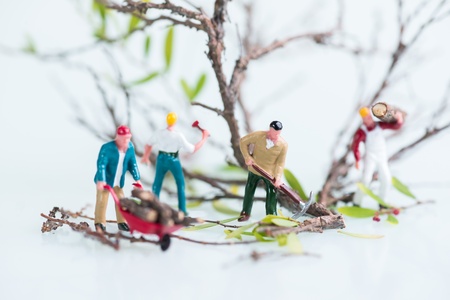 Miniature workmen working together in cutting and carrying logs  
