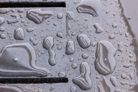 Raindrops pattern and reflection of beams in raindrops and wood grain pattern can be seen through the rain water の写真素材