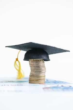 Saving for higher education with Mortarboard on a stack of Euro coins and 20 Euro banknotes の写真素材