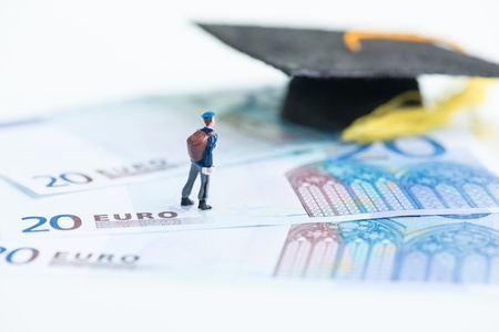 Miniature student standing on top of 20 Euro banknotes and Mortarboardの写真素材