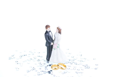 Pure gold wedding rings with porcelain bride and groom figurine backgroundの写真素材