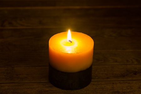 Burning candle on wooden background の写真素材