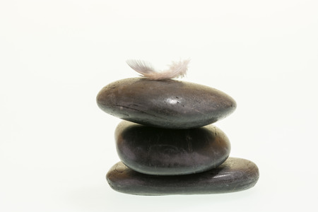 Small feather on black zen stones indicating balanceの写真素材