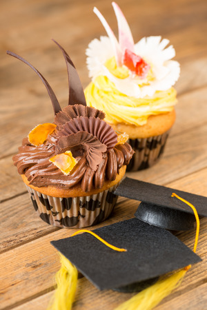 Graduation cupcakes with mortar board on wooden table close-upの写真素材