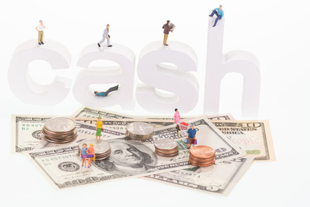 Miniature people on cash wooden letters and US banknotes の写真素材