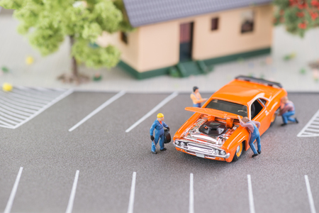 Miniatue mechanics working on a car top view の写真素材