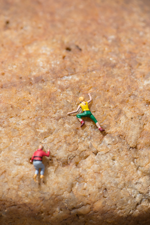 Miniature people climbing the rock on a sunny dayの写真素材