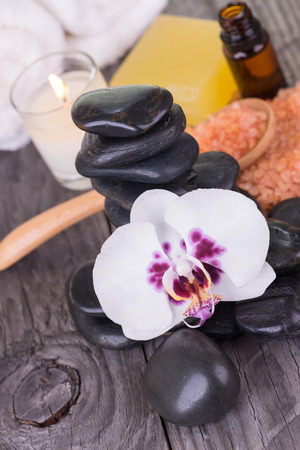 White orchid, bath salt and black stones on weathered deckの写真素材