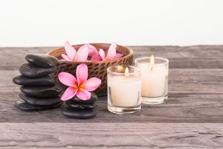 Plumeria flowers, black stones and candles on weathered woodの写真素材
