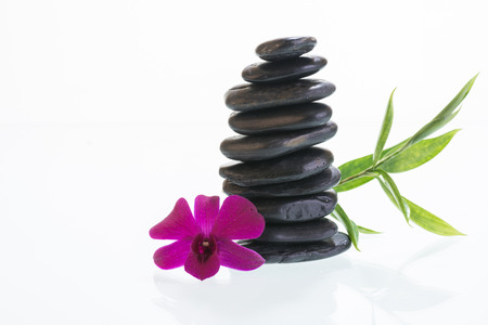Black zen stones with orchid and green leavesの写真素材