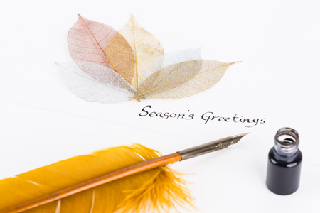 Season's Greetings message and quill pen on cotton paper