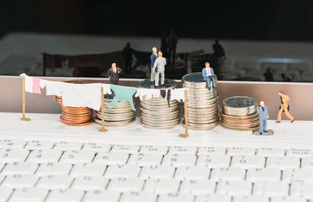 Money laundering concept with miniature men and coins close upの写真素材