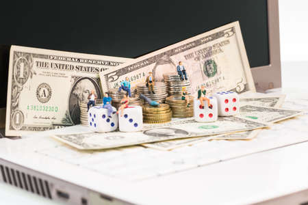 Online gambling concept with miniature people and dice on notebookの写真素材