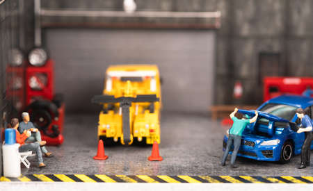 Miniature customers sitting and waiting while the mechanic checking on engine and technician is...