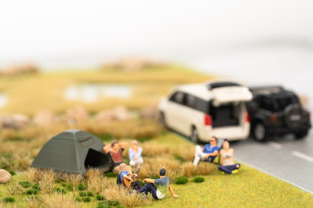 Miniature campers on grassland with vehicles on the roadの写真素材