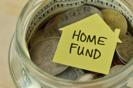 Coins and bills in a jar with label Home Fund - Financial concept
