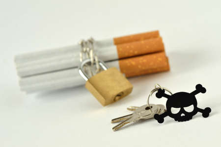 Cigarettes with chain and padlock and key with black skull on white background - Stop smoking...