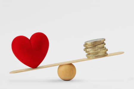 Heart and money on balance scale - Concept of love priority in lifeの写真素材