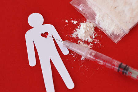 Paper man with heart, syringe and drug sachet on red background - Concept of drug addictionの写真素材