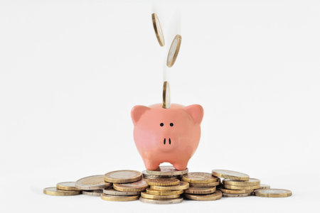 Piggy bank on pile of money and falling euro coinsの写真素材