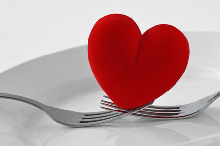 Two forks holding a heart on a plate - Concept of loveの写真素材