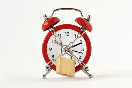 Alarm clock with chain and padlock on white background - Concept of timeの写真素材