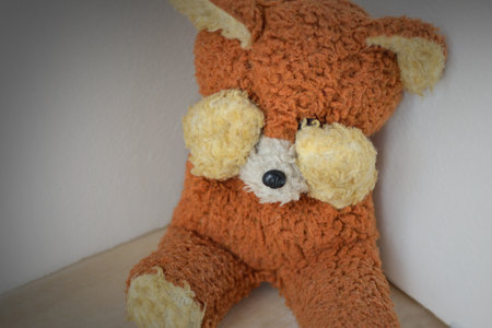 Teddy bear covering eyes in a dark corner - Concept of child abuse and violenceの写真素材
