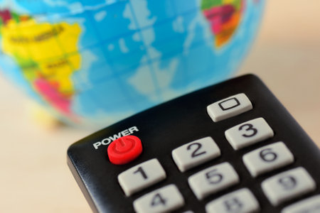 Tv remote control with earth planet in the background - Concept of world control and dominationの写真素材