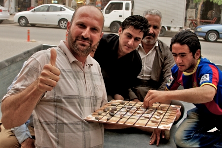 People playing traditional board game with tile and small stones on the streets of Arbil, Autonomous...