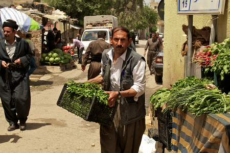 Grocer carrying vegetables to his stand on bazaar (market) in Iraq, Middle East.のeditorial素材