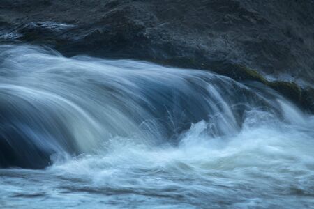 Small waterfall and dark rocks in rapids of the Farmington River, Nepaug Forest, New Hartford, Connecticut.の写真素材