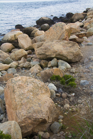 Glacial boulders, rocks and gravel in curving line at water's edge, Hammonasset Beach, Madison, Connecticut.の写真素材