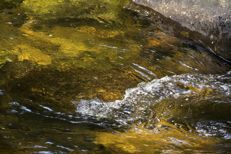 Gentle flow of the Sugar River in Newport, New Hampshire, with colorful underwater rocks and small waves and ripples.の写真素材