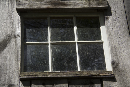 Weathered window with gray wood siding, shed, New England.