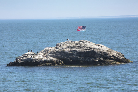 American flag unfurled in the breeze on Wigwam Rock in Niantic Bay in East Lyme, Connecticut.のeditorial素材