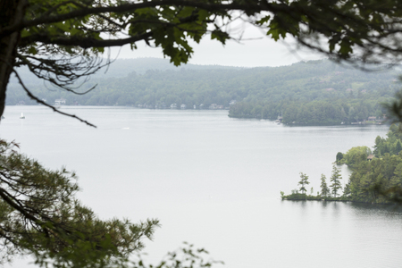 Tranquil view of Lake Sunapee framed by branches, from Clark Landing in New London, New Hampshire.のeditorial素材